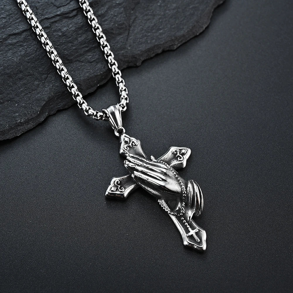 Close up of praying hands cross pendant on stainless steel chain