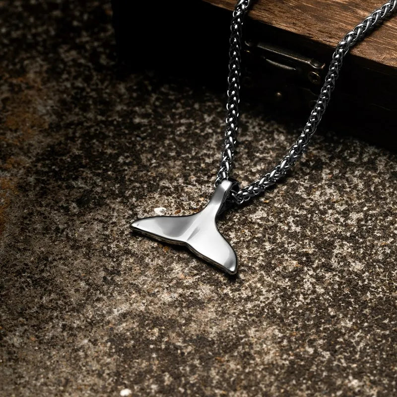 Close up of whale tail ocean pendant necklace on stainless steel chain