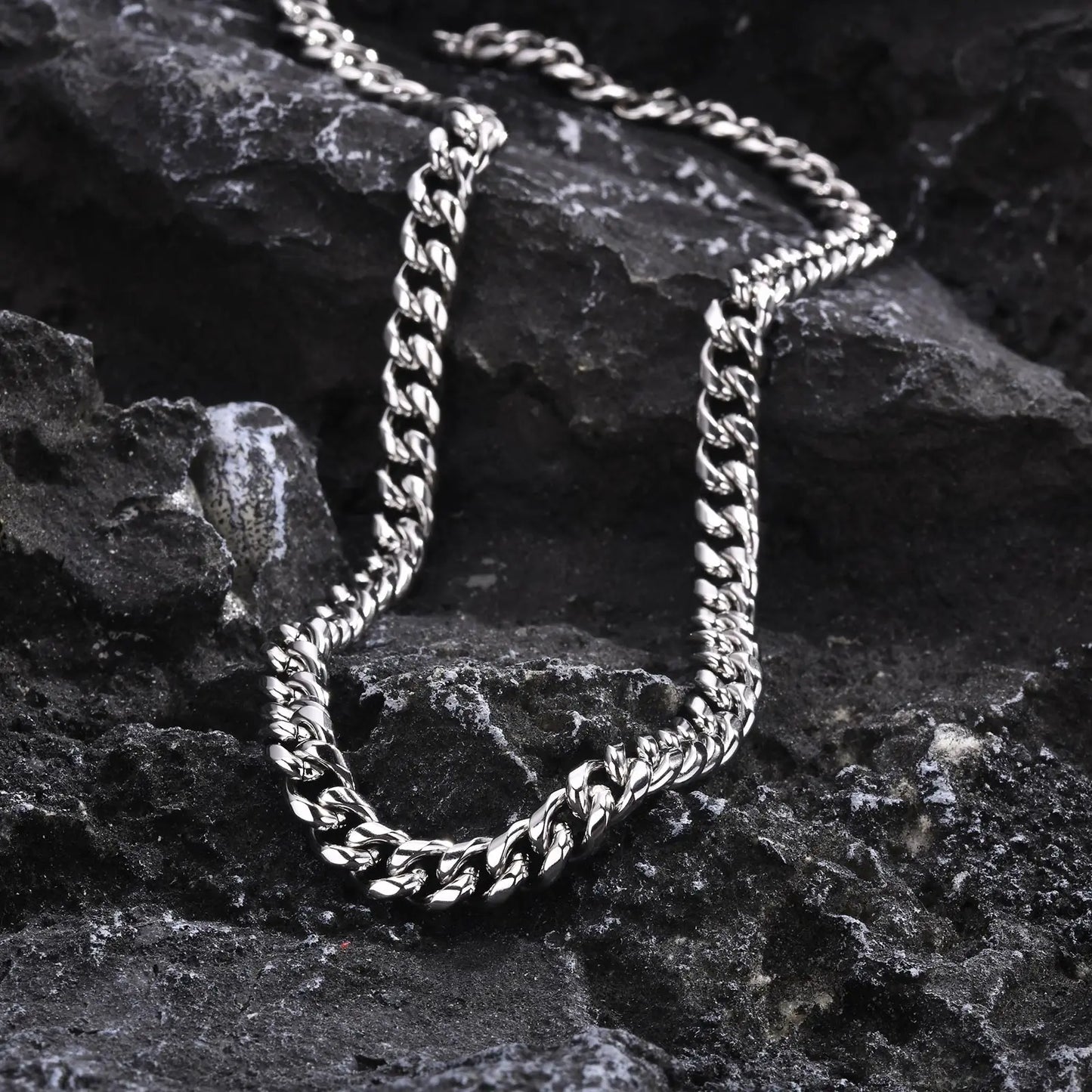 Hip hop style stainless steel Cuban link necklace for men displayed on textured black stone