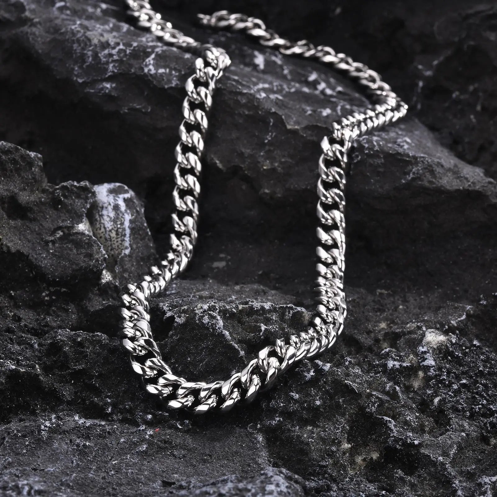 Hip hop style stainless steel Cuban link necklace for men displayed on textured black stone