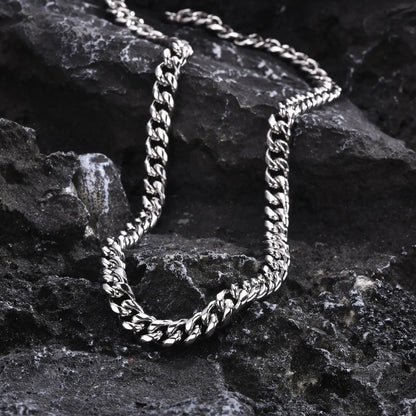Hip hop style stainless steel Cuban link necklace for men displayed on textured black stone